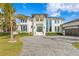 Gorgeous home featuring a pristine white facade, a three-car garage, tropical landscaping, and a paver driveway at 105 Cordova Ne Blvd, St Petersburg, FL 33704