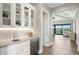 Elegant wet bar with white shaker cabinets, marble countertop, wine fridge, and hardwood floors leading to the waterfront views at 105 Cordova Ne Blvd, St Petersburg, FL 33704