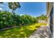 A serene backyard featuring a well-maintained lawn, lush palm trees, and a stone paver walkway at 3604 W Paxton Ave, Tampa, FL 33611