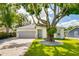 Charming single-story home with a beautiful mature tree in the front yard and a gray two car garage at 3604 W Paxton Ave, Tampa, FL 33611