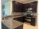 Modern kitchen with dark cabinetry, granite counters, and stainless steel appliances at 8219 Caponata Blvd, Seminole, FL 33777