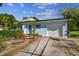 Light blue house with a white garage door, landscaping, and walkway at 5101 W Platt St, Tampa, FL 33609