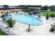 Community pool with lounge chairs, umbrellas and lush landscaping with mature trees at 2104 Hembury Pl # 33, Sun City Center, FL 33573