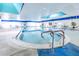 Bright indoor swimming pool with multiple access points, handrails, and ample seating for relaxation at 2104 Hembury Pl # 33, Sun City Center, FL 33573