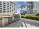 An outdoor kitchen is complete with stainless steel grill, fridge and gray cabinets, set on a tiled patio at 301 1St S St # 1104, St Petersburg, FL 33701