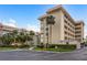 Tan multi-story building with palm trees and parking lot at 620 Edgewater Dr # 304, Dunedin, FL 34698