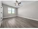 A sunlit bedroom featuring laminate wood floors, a ceiling fan, and a bright window at 12152 Snow Bird Ave, Port Charlotte, FL 33981