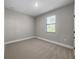 An empty carpeted bedroom, painted gray, features a window with blinds at 12152 Snow Bird Ave, Port Charlotte, FL 33981