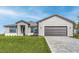 New construction home featuring a modern design, well-manicured lawn, and a two-car garage with brick paver driveway at 12152 Snow Bird Ave, Port Charlotte, FL 33981