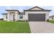 Modern home showcasing a well-kept lawn and a gray brick driveway leading to a two-car garage at 5479 Brussels Ter, Port Charlotte, FL 33981