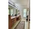 Bathroom featuring double vanity with framed mirrors, neutral tile flooring, and decorative lighting at 2833 Windridge Dr, Holiday, FL 34691