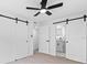 Bedroom with ceiling fan, barn door, and light hardwood floors at 8816 Ashman Rd, Riverview, FL 33578
