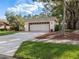 View of the house's garage and driveway, surrounded by lush landscaping at 3358 Tanglewood Trl, Palm Harbor, FL 34685