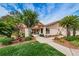 Clubhouse exterior featuring manicured lawn and mature, lush tropical landscaping at 3840 Staysail Ln # 3840, Holiday, FL 34691
