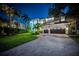 Two-story home featuring an arched entryway, lush lawn, palm trees, a paved driveway, and a two-car garage at dusk at 1100 Monterey Ne Blvd, St Petersburg, FL 33704