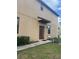 Townhome's side entrance with a brown door and small landscaped area at 10235 Villa Palazzo Ct, Tampa, FL 33615
