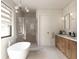 Bright bathroom featuring a modern tub, glass shower, double vanity, stylish fixtures, and large window at 7176 S Shore Dr, South Pasadena, FL 33707