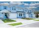 Light blue townhomes with white garage doors, paver driveways, and landscaping at 2509 Mario Way, Clearwater, FL 33761