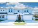 Two-story light blue townhomes with white garage doors and landscaping at 2509 Mario Way, Clearwater, FL 33761