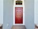 Inviting red front door entryway with a white frame and tiled flooring at 12403 Ballentrae Forest Dr, Riverview, FL 33579