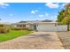 White house with gray metal roof, light blue door, and brick paver driveway at 10088 Paradise Blvd, Treasure Island, FL 33706