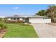 White house with gray metal roof, light blue door, and brick paver driveway at 10088 Paradise Blvd, Treasure Island, FL 33706