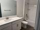 Bright bathroom with a single sink, a quartz countertop, a mirror, and a bathtub with tiled walls at 31684 Griffin Sands Ln, San Antonio, FL 33576