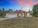 House exterior featuring a tan stucco exterior, large windows, and a three-car garage at 4367 Burns Rd, Brooksville, FL 34602