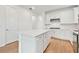 White kitchen with island, stainless steel appliances, and hardwood floors at 9461 Shorebird Ct, Parrish, FL 34219