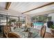 Bright dining area with glass table and chairs, and sliding glass doors that open to the pool area at 910 Oakwood Dr, Largo, FL 33770