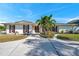 Charming home with a well-manicured lawn, mature palm trees, and a curved concrete walkway at 910 Oakwood Dr, Largo, FL 33770