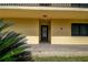 Condo front door with storm door, welcome mat, and decorative palm with rock landscaping at 12300 Vonn Rd # 9105, Largo, FL 33774