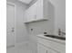 Laundry room with white cabinets and a utility sink at 7214 Blossom Ave, Tampa, FL 33614