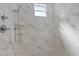 Large shower with marble-look walls and pebble floor at 7214 N Blossom Ave, Tampa, FL 33614