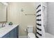 Bathroom with blue vanity, marble counters, and black and white shower curtain at 19807 Gulf Blvd # 128, Indian Shores, FL 33785