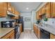 Bright kitchen with wood cabinets, granite counters, and black appliances at 19807 Gulf Blvd # 128, Indian Shores, FL 33785