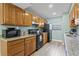 Kitchen with wood cabinets, granite counters, and black appliances at 19807 Gulf Blvd # 128, Indian Shores, FL 33785