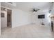 Bright living room features tile flooring, a ceiling fan, and a doorway to the bathroom at 3020 Bonaventure Cir # 102, Palm Harbor, FL 34684