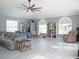 Open-concept living room featuring neutral walls, light flooring, a modern ceiling fan, and lots of windows at 15618 Shoal Creek Pl, Odessa, FL 33556