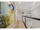 Upstairs hallway with large art piece and wood flooring at 3405 Loggerhead Way, Wesley Chapel, FL 33544