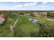 Aerial view of a golf course community with houses, roads, and a pond at 5935 Precious View Ct, New Port Richey, FL 34655