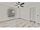 Bright bedroom featuring light wood floors, a modern ceiling fan, and a double closet at 7231 Big Bend Dr, Spring Hill, FL 34606