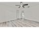 A bright bedroom features updated gray wood-look floors, white walls, and a ceiling fan at 7231 Big Bend Dr, Spring Hill, FL 34606