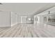 Spacious living area with wood-look floors, white walls, and views into the kitchen and hallway at 7231 Big Bend Dr, Spring Hill, FL 34606