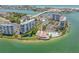 Expansive aerial view showcasing waterfront condos, a swimming pool, tennis courts, and a marina on a peninsula at 9415 Blind Pass Rd # 905, St Pete Beach, FL 33706