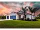 Two-story home with attached garage and landscaped lawn under a vibrant sunset at 174 Green Oak Park, Rotonda West, FL 33947