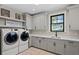 Laundry room with gray cabinets, washer, dryer, and herringbone floor at 5104 Homer W Ave, Tampa, FL 33629