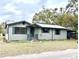 Charming single-story home featuring light green siding, dark trim and shutters, and a metal roof at 18802 3Rd Se St, Lutz, FL 33549