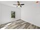 Bright bedroom with ceiling fan, large window, and grey wood-look floors at 5364 Boxtree Ct, Dade City, FL 33523