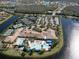 Stunning aerial view showcasing a community clubhouse with pools, tennis courts, and ample parking surrounded by lakes and lush landscaping at 16233 Amethyst Key Dr, Wimauma, FL 33598